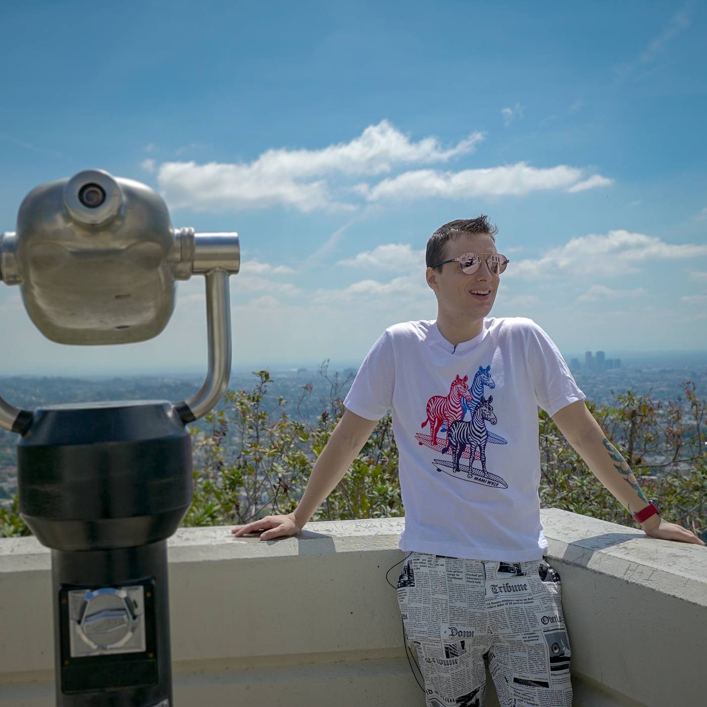 Mikhail at a city lookout beside a coin telescope