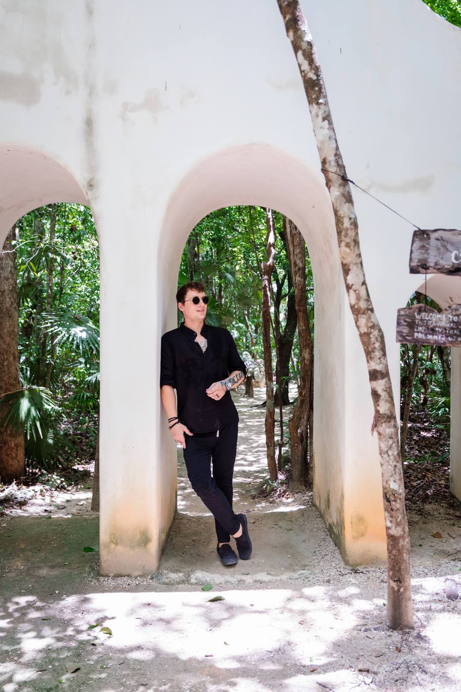 Mikhail leaning in a white arch in the jungle